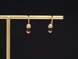 a pair of black and gold earrings on a wooden stand