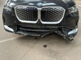 the front end of a black bmw suv with a denting front bumper
