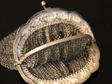 a silver purse with a chain around it on a black surface