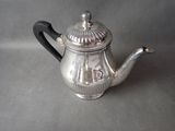 a silver tea pot with a black handle on a table
