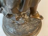 bronze statue of a woman holding a bird on a white surface