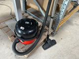 un aspirateur noir et rouge posé sur une palette dans un entrepôt