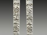 paire de colonnes en pierre sculptées, ornées de visages et de feuilles