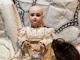 a doll that is sitting next to a doll on a bed