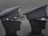 pair of police hats on mannequin heads against a gray background