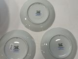 four white plates with different designs on them sitting on a table