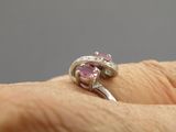 la main d'une femme tenant une bague en diamant rose et blanche