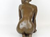 bronze statue of a woman sitting on her knees on a white background