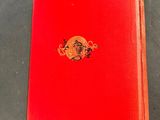 an old red book sitting on top of a table next to a cup of coffee