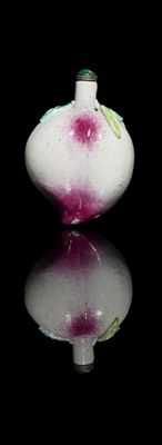 a white vase with a pink flower on it on a black surface