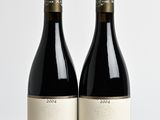 two bottles of wine sitting on top of a table next to each other