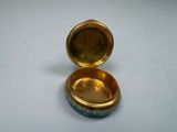 a gold and blue box with a lid on a white table