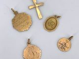 a group of four gold charms including a cross, a medal, and a coin