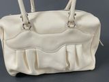 beige leather handbag with pleated handles on a grey background