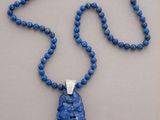 necklace with blue beads and a pendant with a silver clasp on a gray background