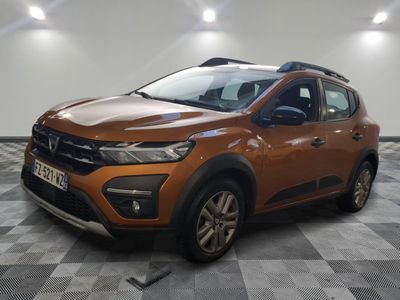 la voiture orange est garée sur le sol en damier d'un garage