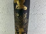 un vase noir et doré posé sur une table blanche