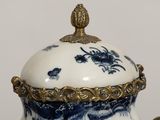 a blue and white vase with a gold lid