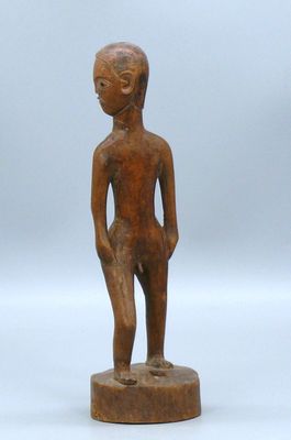 une petite statue en bois représentant un homme debout sur un socle en bois