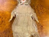 an old fashioned doll sitting on top of a wooden table
