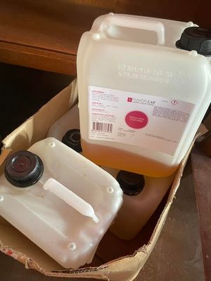 two containers of liquid sitting in a box on the floor