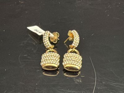 une paire de boucles d'oreilles dorées posées sur un fond noir