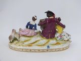 a figurine of two people sitting on a bench with a dog
