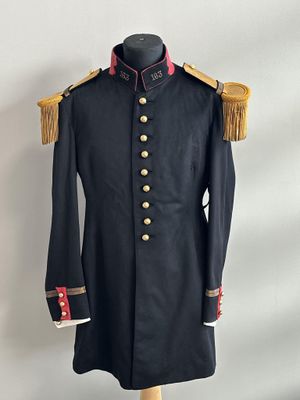 un manteau militaire noir avec des boutons dorés et des franges, posé sur un présentoir pour mannequin