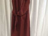 une robe rouge suspendue à un cintre devant un rideau blanc
