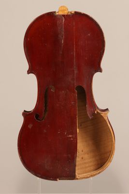 an old violin is sitting on a stand on a white surface
