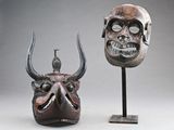 paire de masques africains ornés de cornes et d'un crâne, posés sur un socle