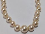 a close up of a white pearl necklace on a white surface