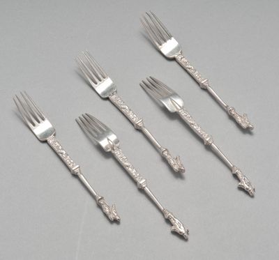 six fourchettes et un couteau posés sur une table devant un fond gris
