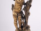 an antique bronze figurine of a cupid holding a tree branch