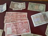 several different bank notes are on a table with a red surface