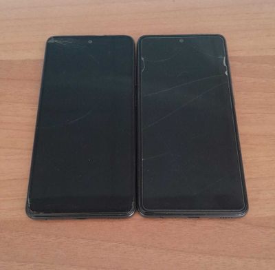 two black iphones sitting side by side on a wooden table