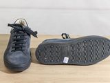 black leather sneakers with laces and rubber soles on a wooden table