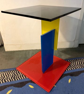 une table avec un plateau noir et un piètement rouge et bleu