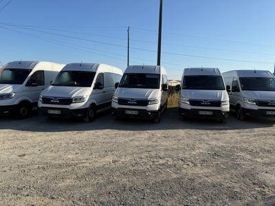 Plusieurs fourgonnettes blanches sont garées en rangée sur un parking