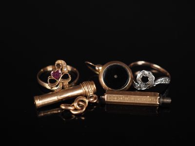 two gold rings and a black stone ring on a black surface