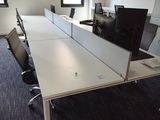 a room with a desk, chairs, and a monitor on the wall