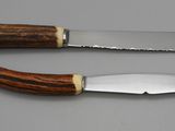 two knives with wooden handles sitting on top of a table