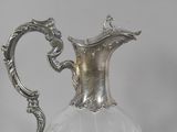 a silver and glass pitcher with a handle on a table