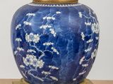 a blue and white vase with a gold base on a table