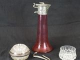 un vase en verre rouge et une assiette en argent sur fond noir