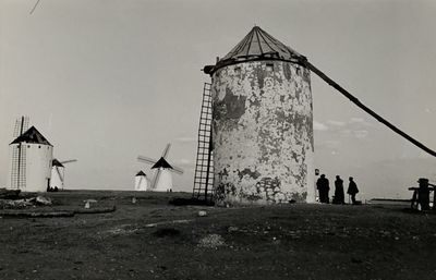 photo en noir et blanc d'un groupe de personnes debout devant un moulin à vent
