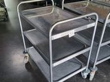 three metal trolleys are sitting in a room with a painting on the wall
