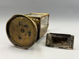 une vieille horloge en laiton avec une vitre cassée à côté