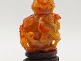 an orange jade figurine of a dragon on a stand