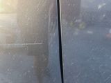 a car door handle with a reflection of a person in the background